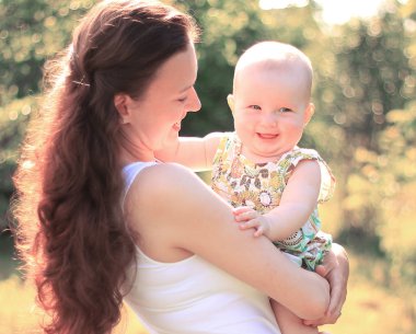 Anne ve mutlu bir yaşındaki kızı parkta bir yürüyüş üzerinde gülümseyen