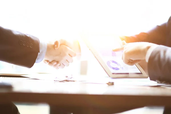 Businessman with a financial schedule on the background of a handshake of business partners — Stock Photo, Image