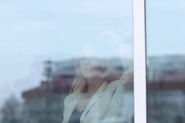 Detrás del cristal. joven mujer de negocios mirando por la ventana de la oficina — Foto de Stock