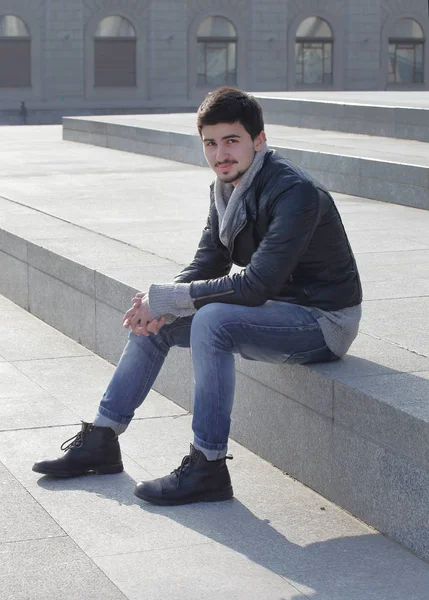 Young man sitting on the steps near the College — Stock Photo, Image