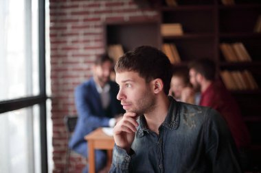 Düşünceli genç tasarımcı ofis penceresinden dışarı bakıyor..