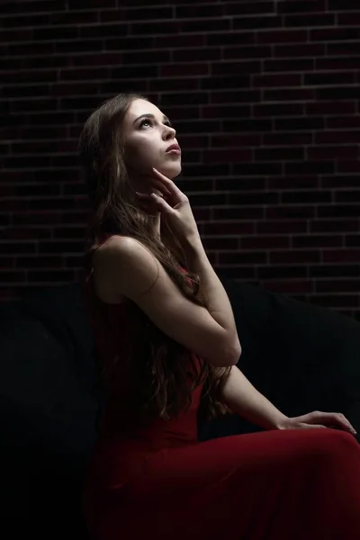 Стильна молода жінка в червоній сукні сидить у кріслі — стокове фото