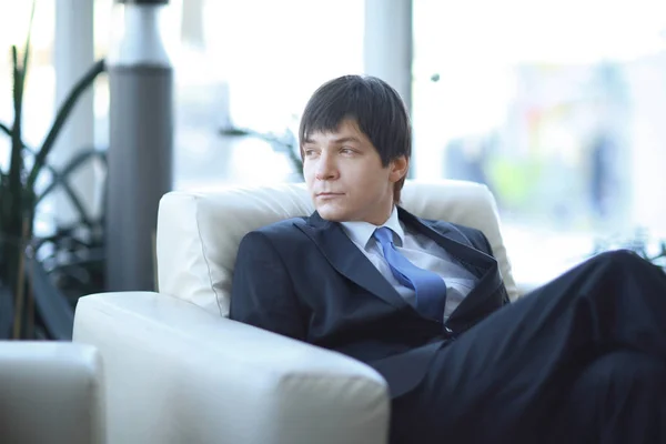 Moderní podnikatel sedí v křesle v hale moderní kancelář. — Stock fotografie