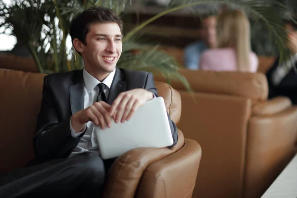 Крупный план молодого бизнесмена с помощью цифрового планшета, сидящего в фойе банка — стоковое фото