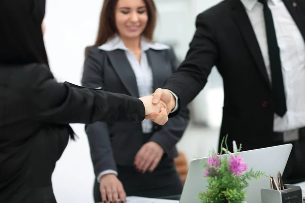 Zwei Geschäftsfrauen beim Händeschütteln über einen Schreibtisch, während sie ein Geschäft abschließen — Stockfoto