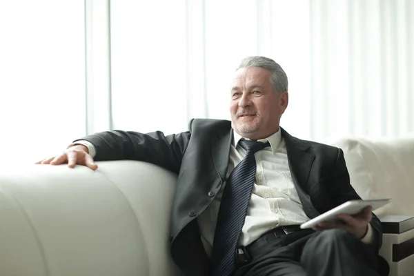 Successful businessman sitting on sofa in modern office — Stock Photo, Image