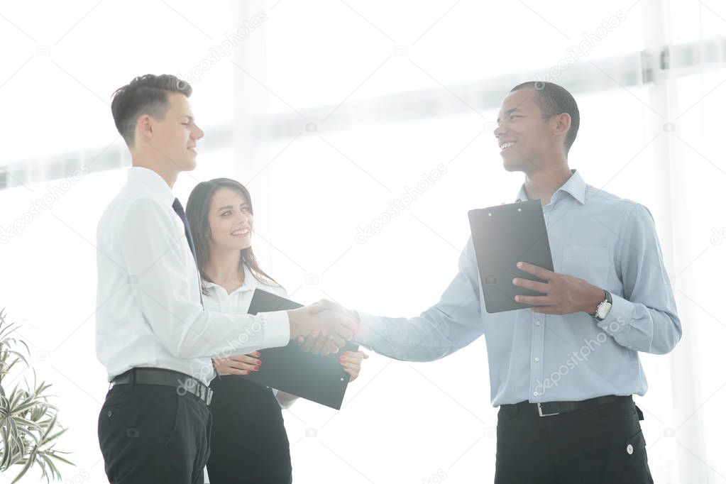 friendly business people shaking hands on blurred background