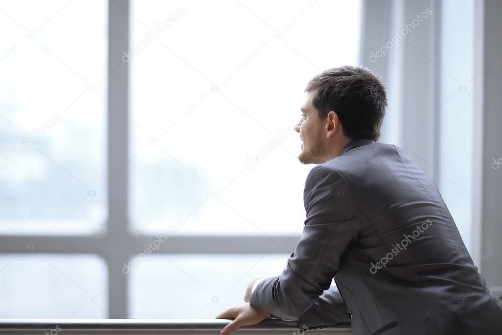 Businessman standing near the window and looking into it