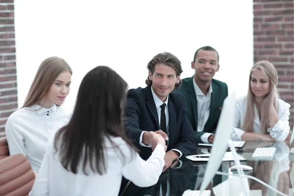 Apretón de manos a las mujeres de negocios con su socio en la mesa de negociaciones — Foto de Stock