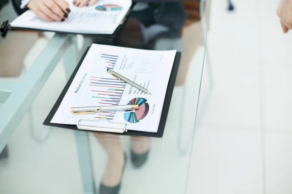 Pennen en financieel verslag op de glazen tafel in het kantoor — Stockfoto