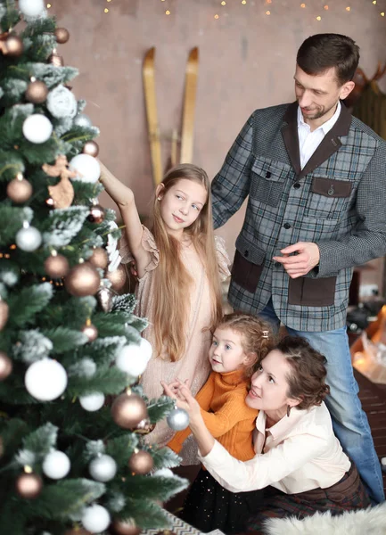 Gelukkig familie versiert de kerstboom in hun woonkamer. — Stockfoto