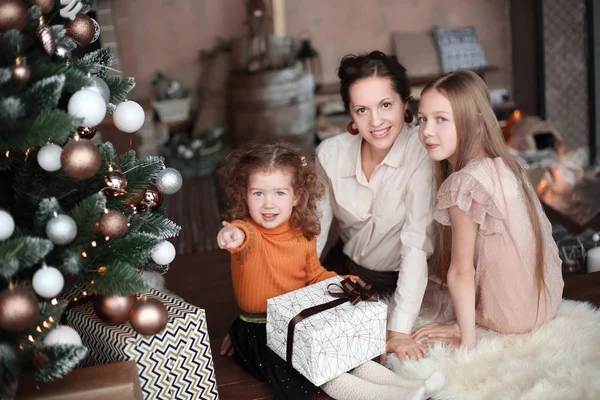 Matka a její dcery otvírají dárkovou krabici u vánočního stromečku — Stock fotografie