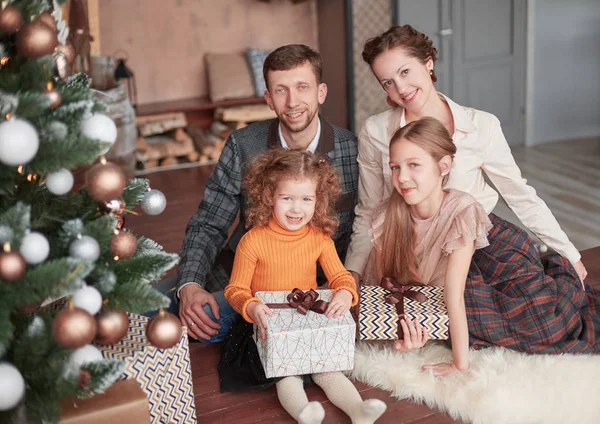 Familia feliz sentado cerca del árbol de Navidad en el acogedor salón — Foto de Stock
