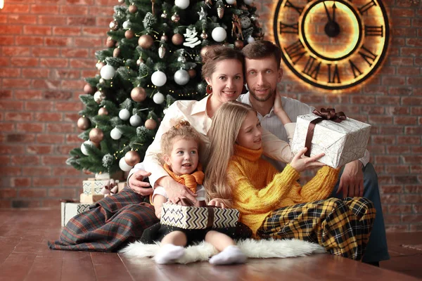 Dvě sestry a jejich rodiče sedí u vánočního stromku — Stock fotografie
