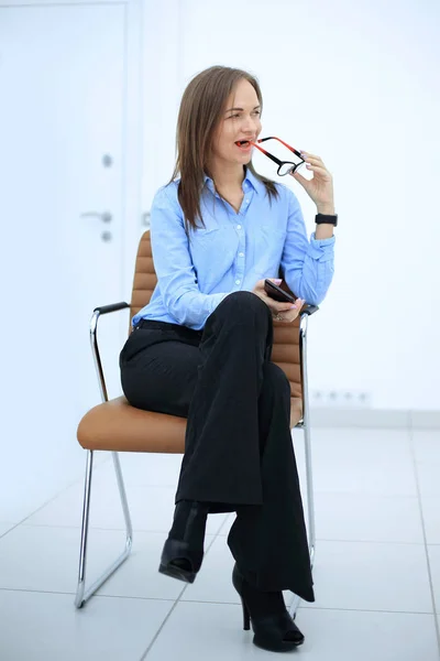 serious business woman with smartphone sitting on an office chair