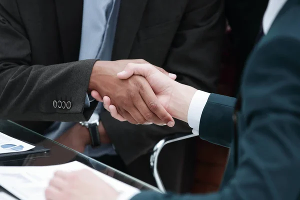 Handelspartner per Handschlag vor dem Hintergrund des Arbeitsplatzes — Stockfoto