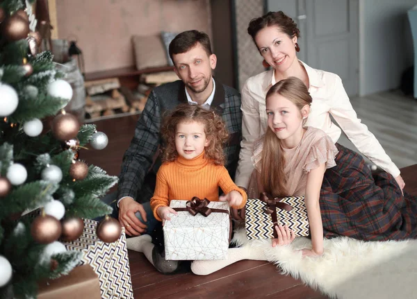 Familia feliz sentado cerca del árbol de Navidad en la noche de Navidad — Foto de Stock