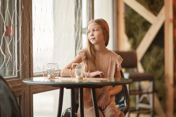 Милая девушка сидит за столом в кафе — стоковое фото