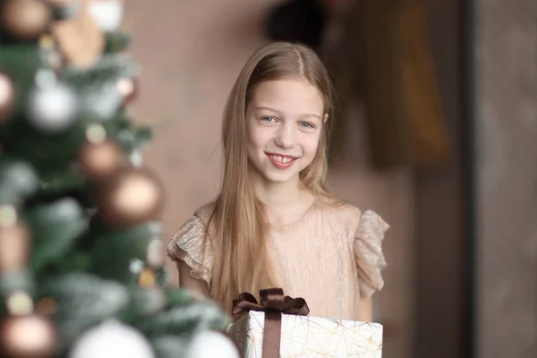 Szczęśliwa dziewczyna z prezentem świątecznym stojąc w pobliżu choinki — Zdjęcie stockowe