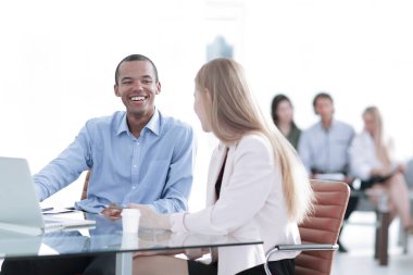 Genç ve güzel iş ortakları dizüstü bilgisayar kullanıyor, belgeleri tartışıyorlar.