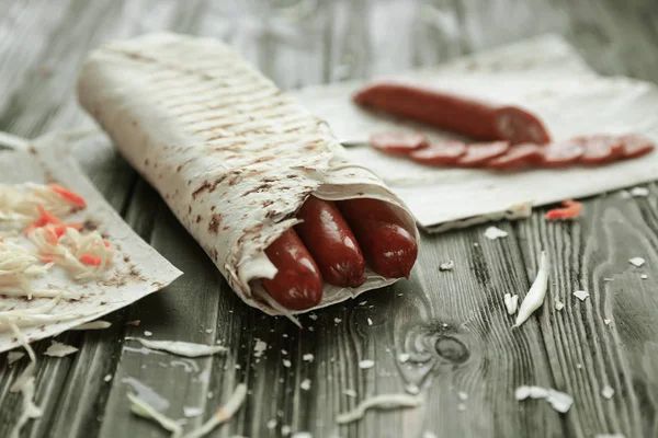 spicy sausages in pita bread on a wooden table