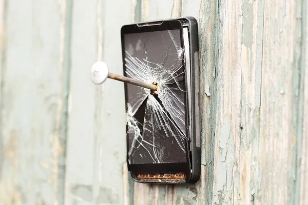 obsolete mobile phone is nailed to a wooden fence