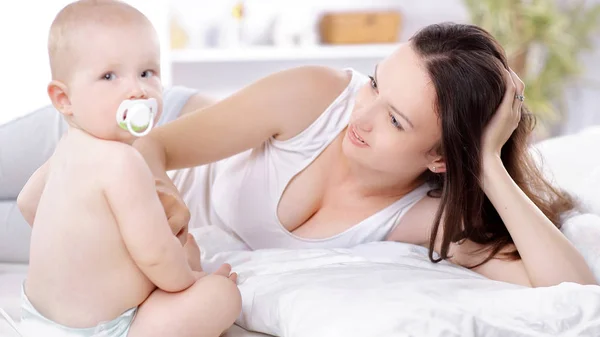 Gelukkig moeder praten met de baby liggend op het bed — Stockfoto