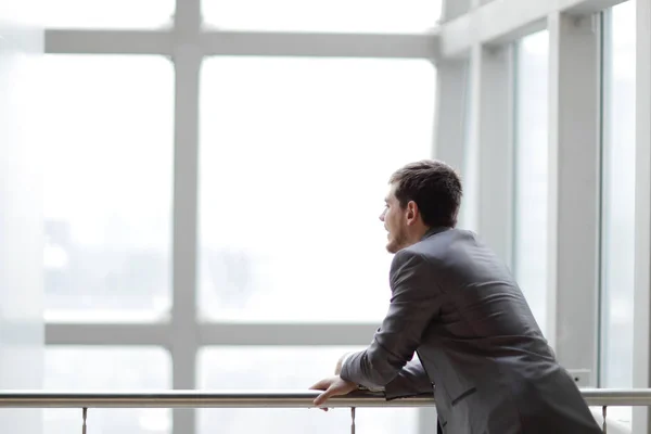 Empresario de pie cerca de la ventana y mirando en él —  Fotos de Stock