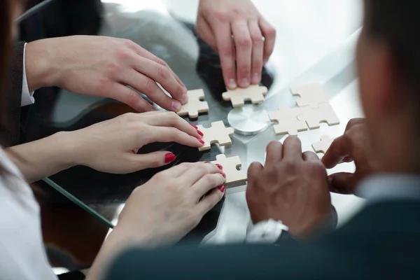 Vicino. team di lavoro assemblaggio pezzi puzzle . — Foto Stock