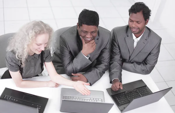 Mitarbeiter schauen auf Laptop-Monitor, sitzen am Tisch — Stockfoto