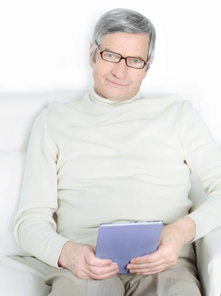 Home life of an elderly person. Reading a book on the couch — Stock Photo, Image