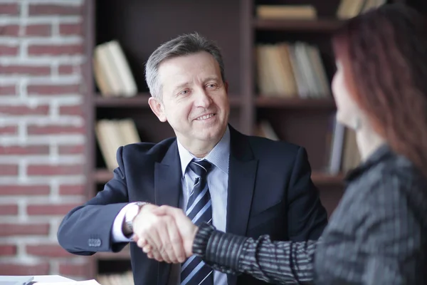 Handschlag mit Geschäftspartnern am Schreibtisch im Büro. — Stockfoto