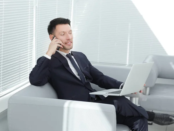 Empresário falando em um telefone celular, sentado no lobby do hotel — Fotografia de Stock