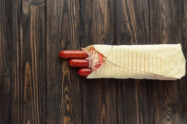 Smoked sausage in pita bread on a dark wooden background.photo w — Stock Photo, Image