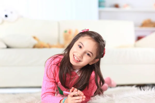 Close up.little girl draws lying on the floor in the room — Stock Photo, Image