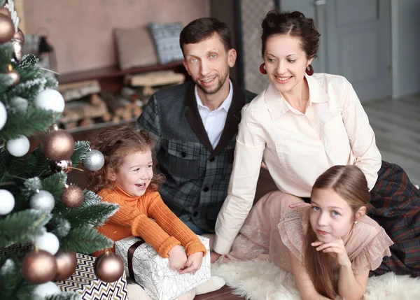 Feliz familia sentada junto al árbol de Navidad —  Fotos de Stock