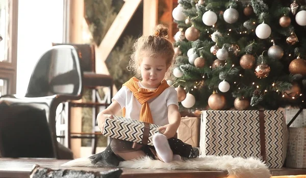 Dziewczynka bawi się prezenty w pobliżu choinki — Zdjęcie stockowe