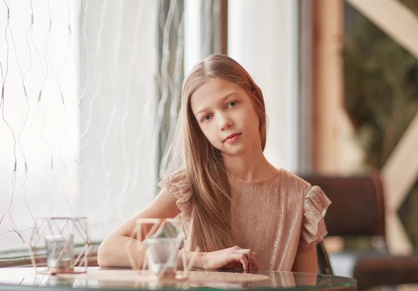 Cute girl sitting at a table in a cafe — Stock Photo, Image