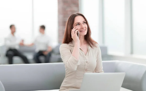 Joven mujer de negocios se comunica con sus socios utilizando el ordenador portátil y el teléfono inteligente — Foto de Stock