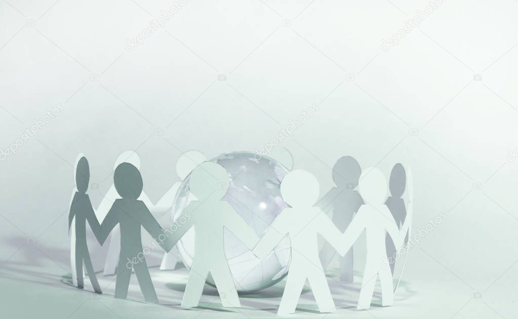 team of paper doll people holding hands around the planet