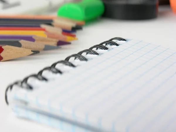 Close-up da imagem borrada do bloco de notas quadriculado e lápis no fundo branco — Fotografia de Stock