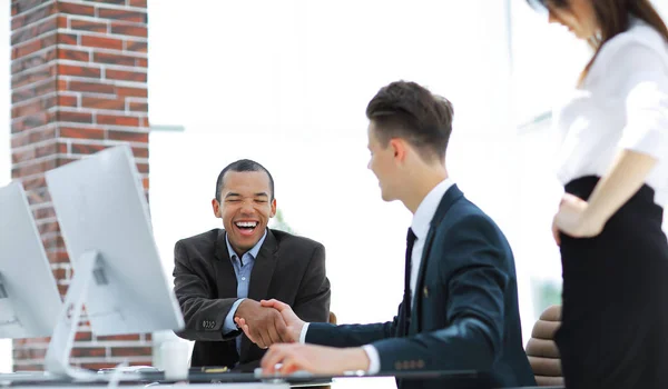 Apretón de manos socios comerciales internacionales en un escritorio — Foto de Stock