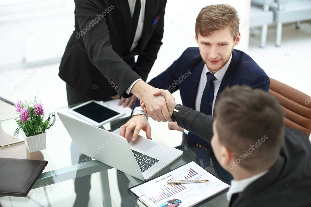 Managers and clients handshakes over the Desk in the Banks office