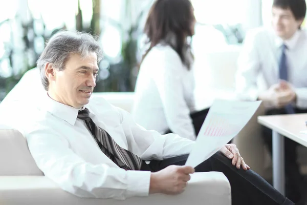 Homme d'affaires réfléchissant à un document assis dans un bureau moderne — Photo