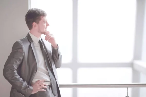 Sonriente hombre de negocios de pie cerca de una gran ventana de oficina — Foto de Stock