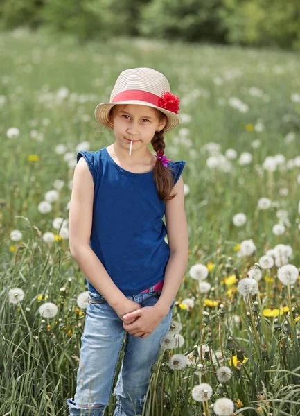 Petite fille dans un chapeau de paille, debout sur une prairie verte — Photo