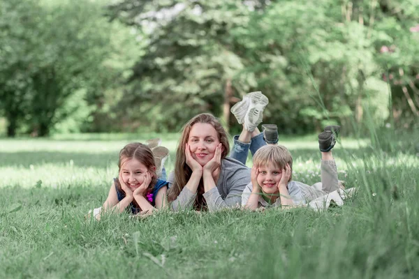 Mamá divertida con sus hijos en el césped en un día de verano —  Fotos de Stock