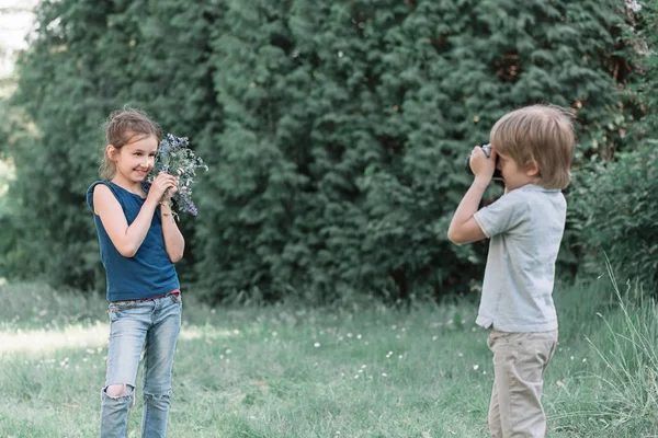 Kleiner Junge fotografiert seine Schwester im Park. — Stockfoto