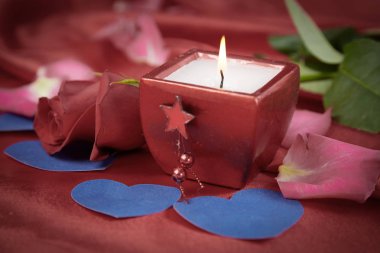 kırmızı ipek arka planda mum ve gül