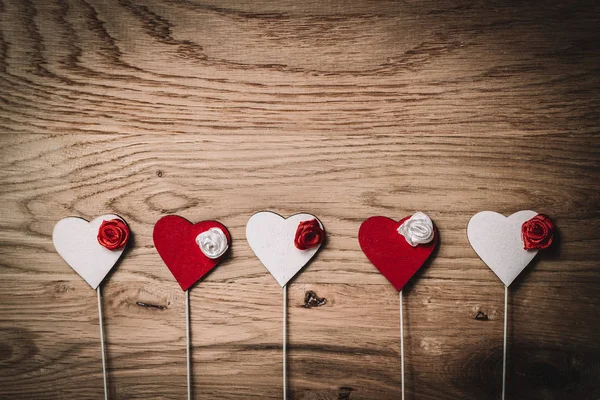 Linha de corações vermelhos e brancos com paus no fundo de madeira — Fotografia de Stock